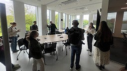 A student talking to a group of reporters in a white classroom with lots of natural light