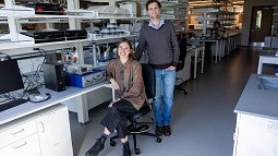 Two people standing at a bench, with some electronic equipment