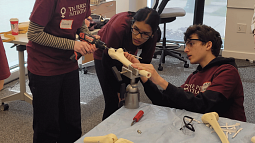 Student drills into artifical bone as two students look on