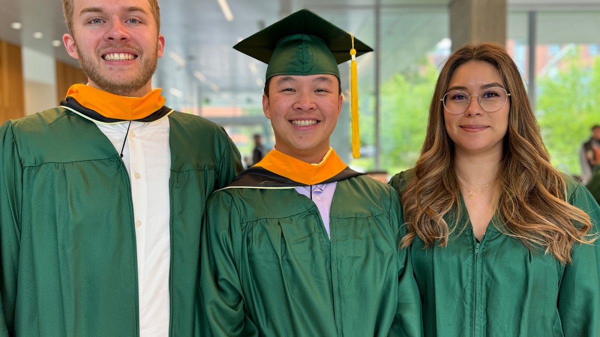 Trio of smiling grads in green regalia