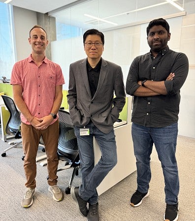 Three people standing shoulder to shoulder in a business office 