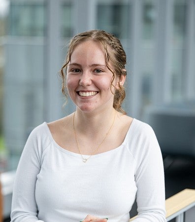headshot of woman in a white top with curly hair
