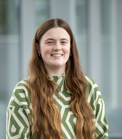 Headshot of a woman in a grey and white patterned top