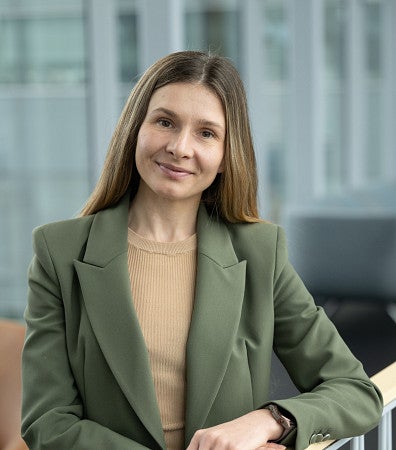 headshot of a woman with blonde hair, in a green blazer and a tan tanktop