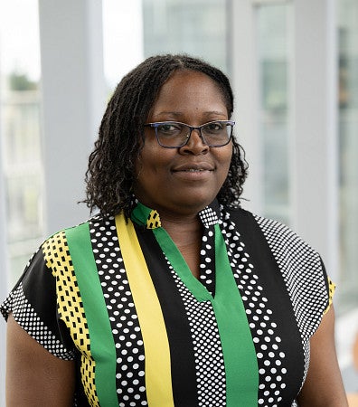 Headshot of a woman, with glasses, with a yellow, green and black top
