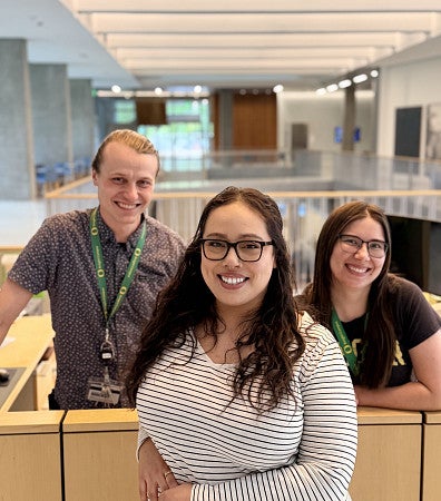 three smiling people in front of lobby reception desk