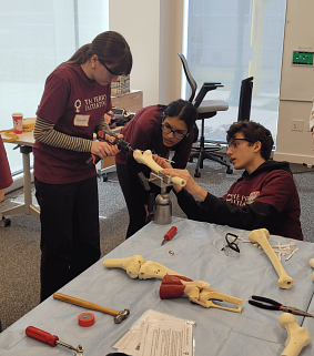 Student drills into artifical bone as two students look on