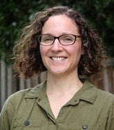 Headshot of a woman with curly hair and glasses