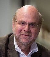 headshot of an older white man, with glasses, in a blazer