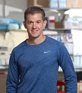 headshot of a man in a blue shirt, in a lab
