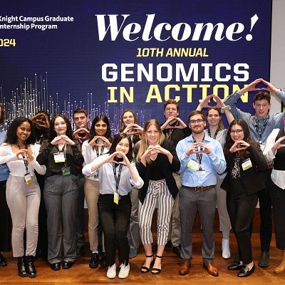 Group of students throwing the O in front of Genomics in Action slide