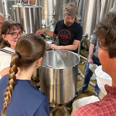 Students stand around a pot in a brewery learning how to make beer
